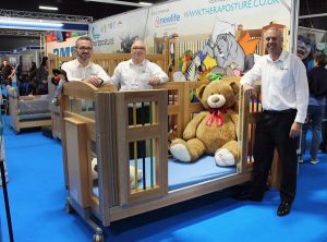 Salesmen stood around a cot with teddy bear