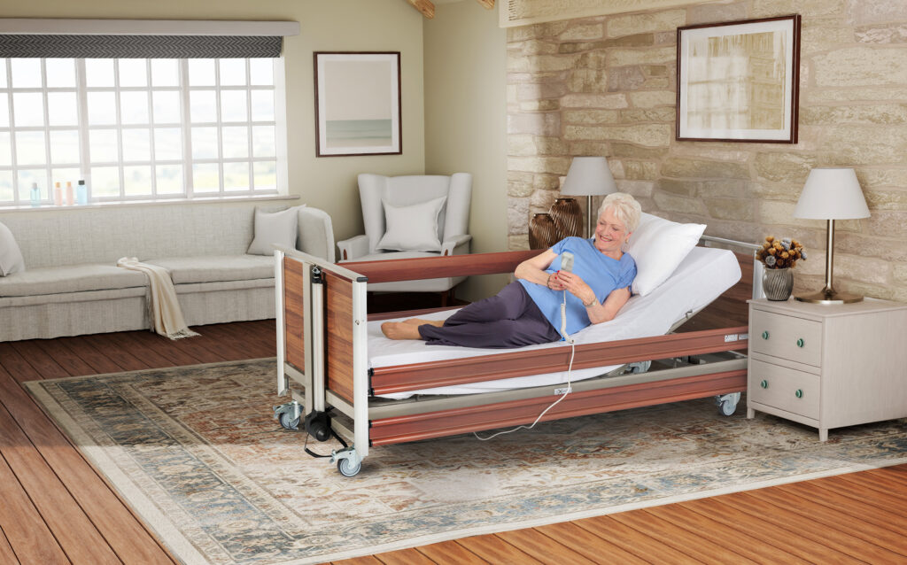 Woman laying in an adjustable bed with protective side lowered, holding hand control